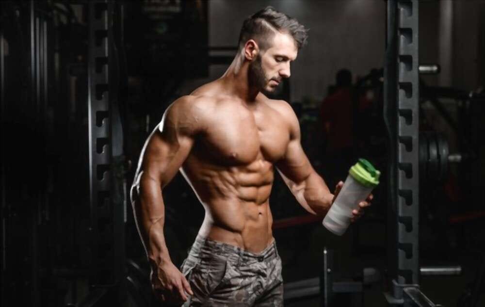 Agoge Diet — A young man with a wonderful body and bottle in hand at gym.