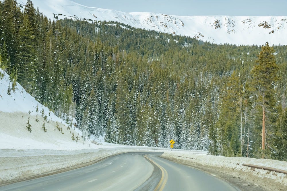 Photo of a road through a snowy, mountainous forest