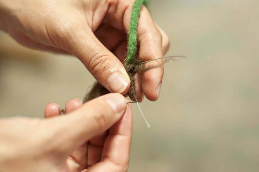 Carefully wrapping wool around a wire to create plant roots.