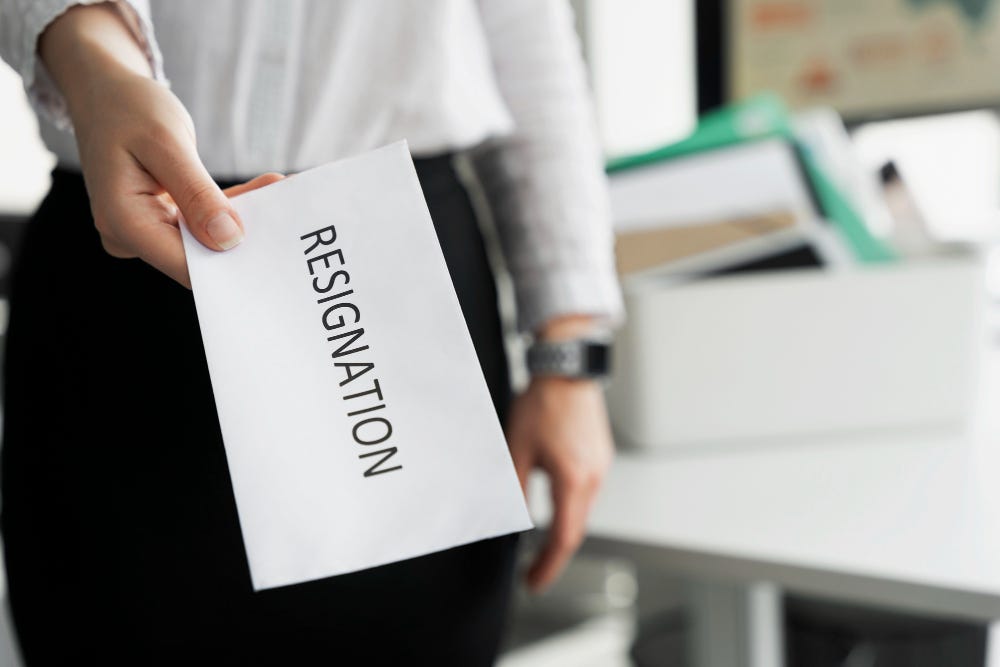 Image of hand of businessperson holding out a resignation note toward the viewer.