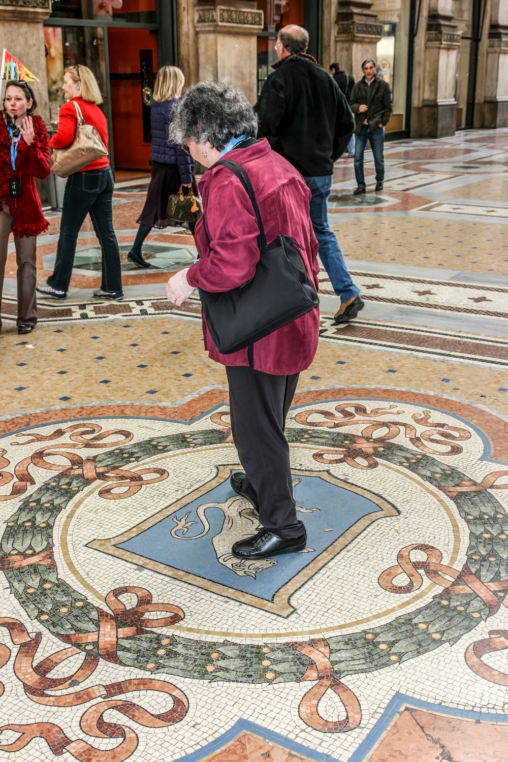 A woman spins on the image of a bull on the floor in the exact middle of the Galleria Vittorio Emanuele II.