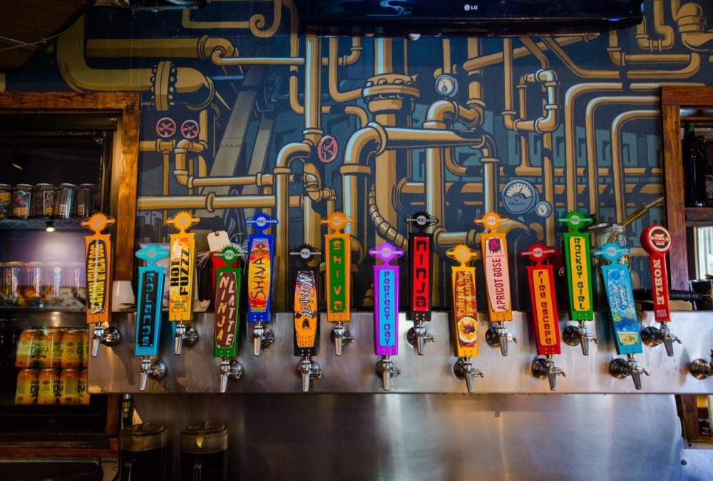 15 colorful taps at the bar of a craft brewery.