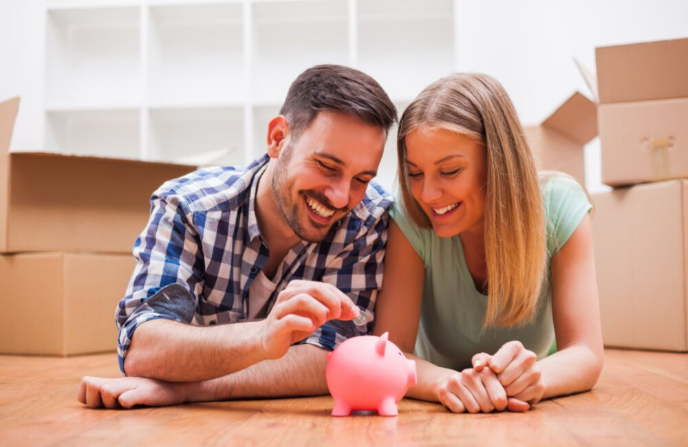 Engaged couple — saving money for a wedding. Putting change into a piggy bank.