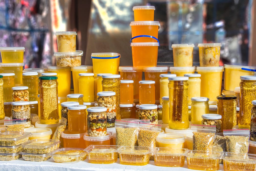 A variety of natural raw honey in glass jars and plastic containers.