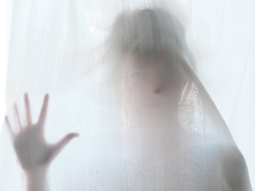 A woman behind an opaque sheet, looking like a ghost