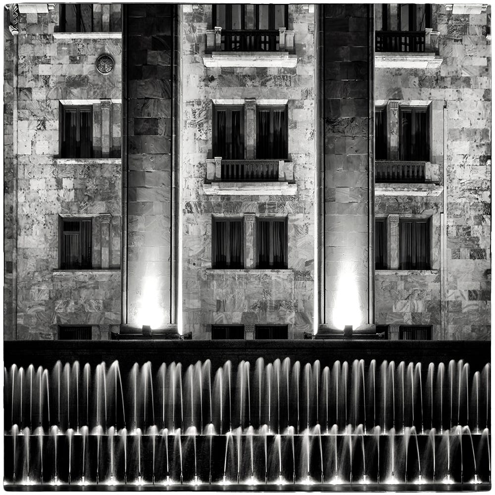 Black and white image of the Parliament of Georgia facade and row of fountains at night in Tbilisi, Georgia