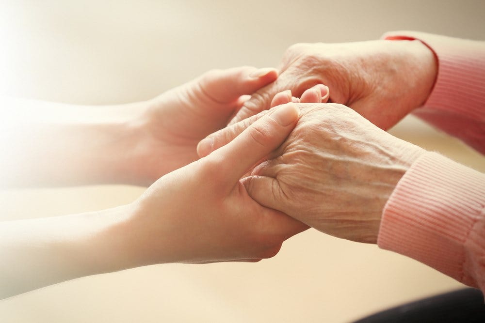 Carer holding hands of elderly person being cared-for