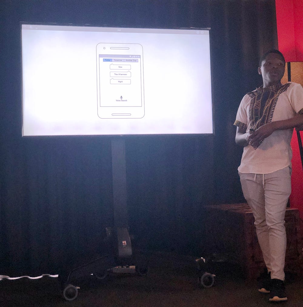Student presenting in front of a screen which shows a mobile wireframe.