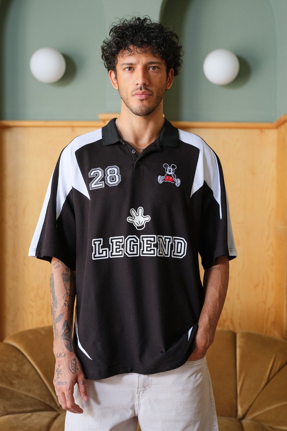 A man wearing a black and white polo Mickey Legacy Polo Jersey from Bonkers Corner, looking stylish and casual.