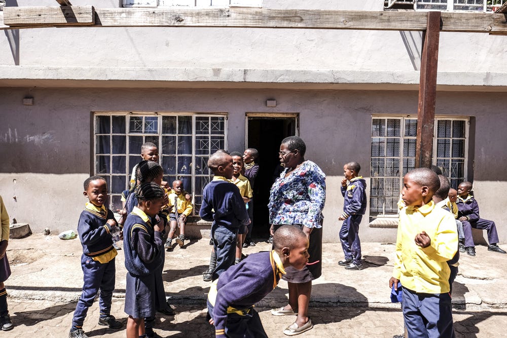 Judith Manjoro talks with students during the break in the courtyard of Velamfundo Primary School in Yeoville, Johannesburg, on 8 October 2019. The school welcomes migrant children who were not admitted to South African public schools because their parents are not able to produce documents such as birth certificates or immunization cards, or pay school fees demanded by private schools. Photo by Miora Rajaonary