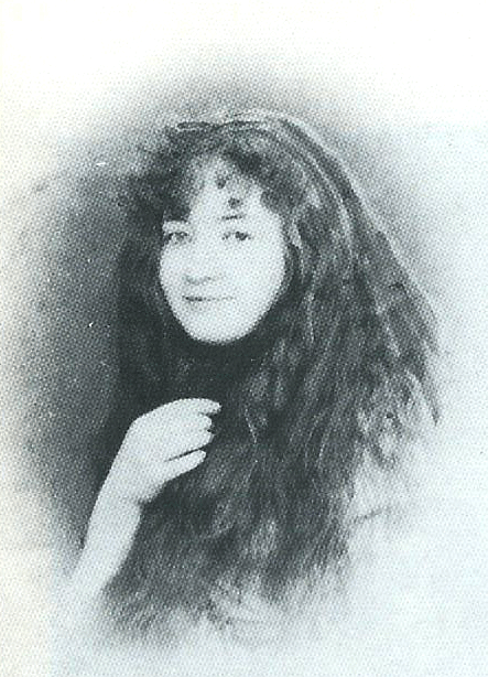 Old black and white photograph of a smiling young girl with loose dark hair