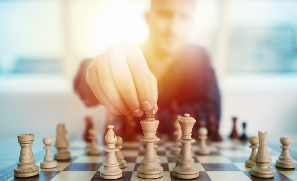 A man playing chess and holding a chess piece.