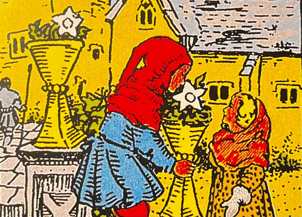The VI of cups from the Rider-Waite-Smith Tarot Deck — Two children in a village garden. One is holding a cup with a single white flower and smelling the flower.