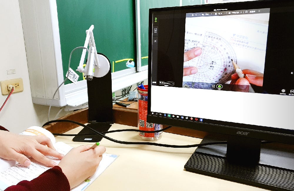 A math teacher using a protractor and pencil from her desk to teach the students how to measure angles.