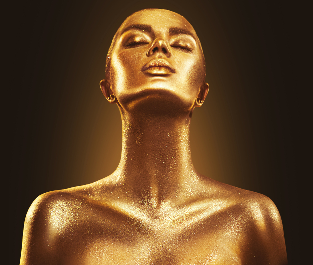 A lady painted gold looking up to the heavens, with gratitude.