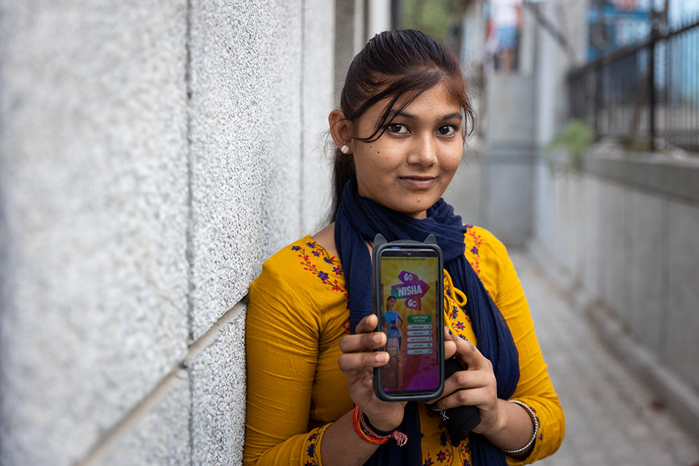 A girl holds a cell phone that displays a mobile game that teachers girls about menstruation.