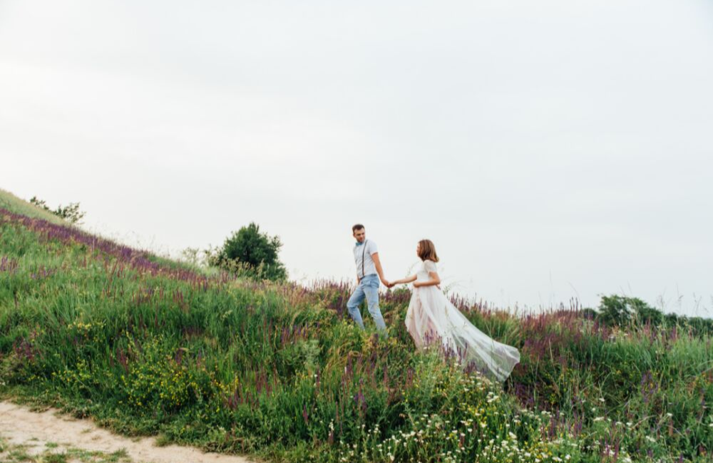 Casual wedding photo in a field. Bride and groom walking through a field in a casual outdoor wedding.