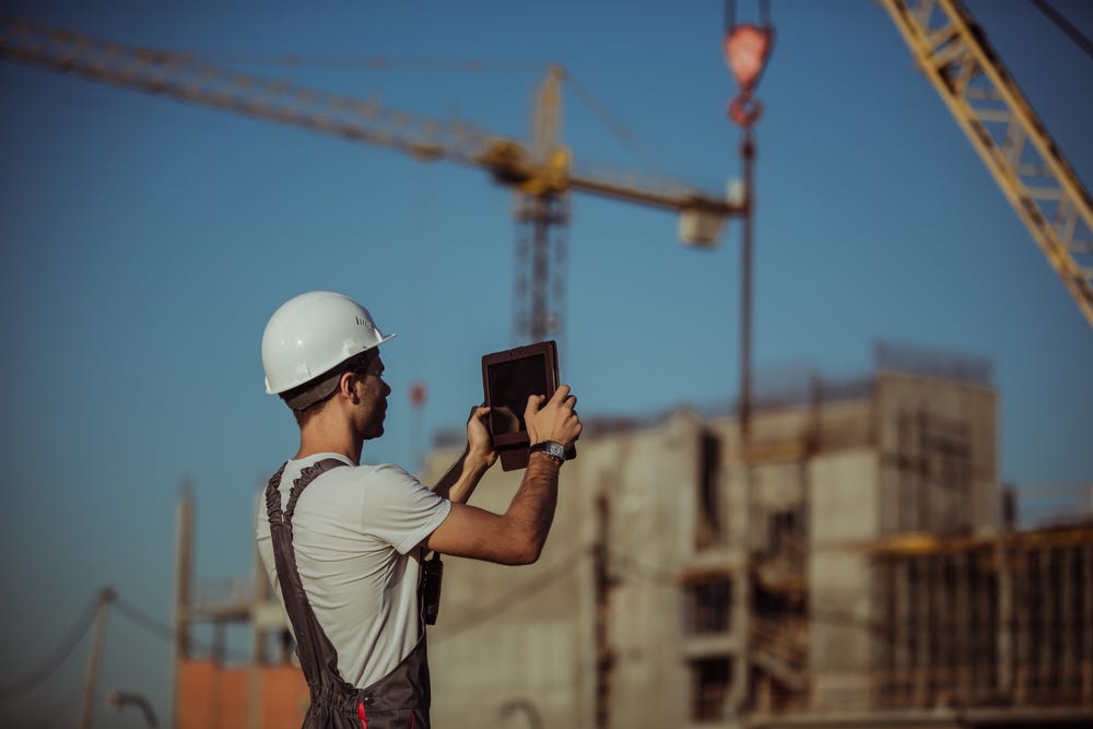 Worker taking a picture with an iPad on a construction site