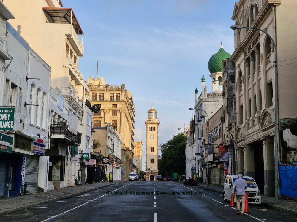 Old Colombo Lighthouse and Clock Tower, a historic landmark with a tall, clock tower with a glass walled lighthouse dome, against a backdrop of clear skies