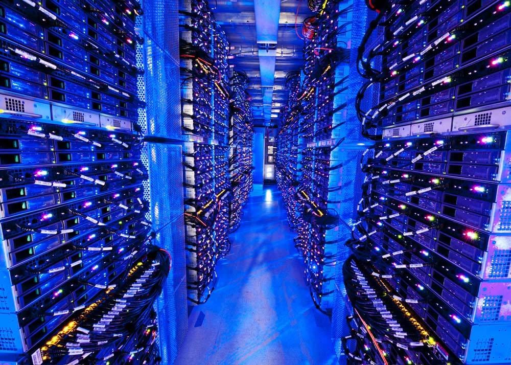 A room with floor-to-ceiling stacks of technology. The room is lit blue.