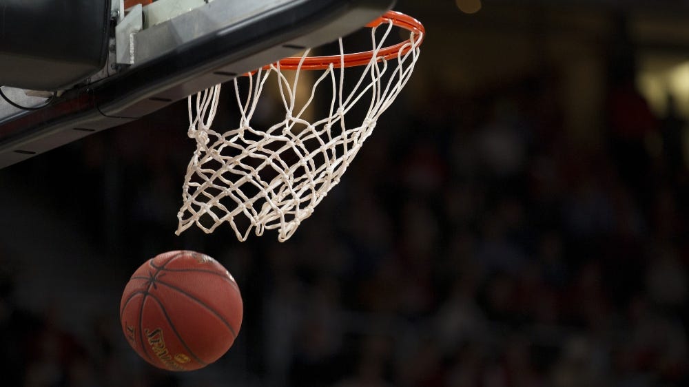 Foto do momento em que uma bola de basquete entra na cesta.