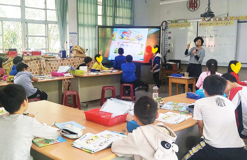 A pair of students using the VZ-1 HD document camera to display their English workbook to the class while the teacher conduct