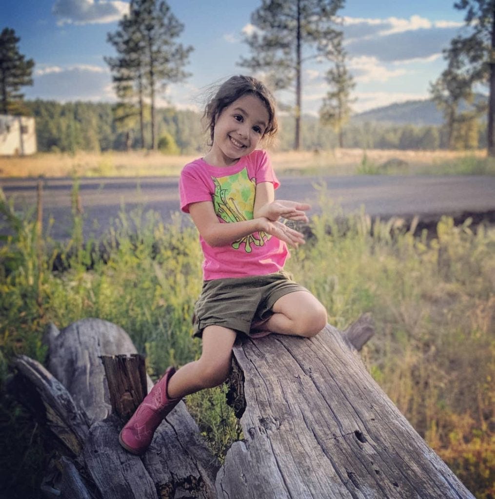 4 year old Lucia plays on a log while camping