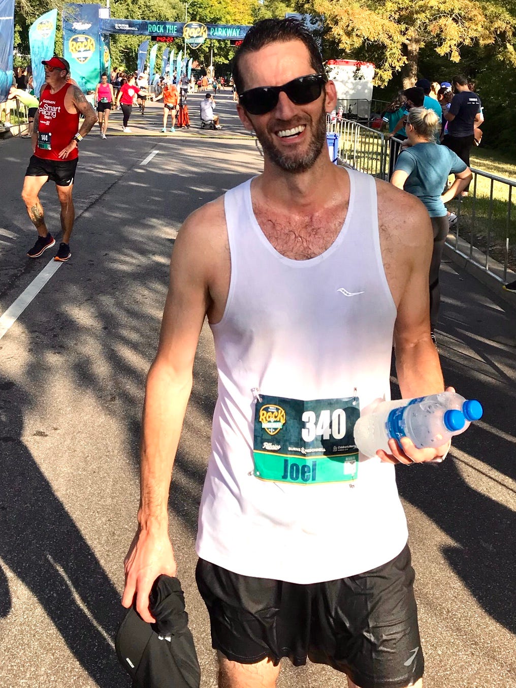 Photo of a very sweaty Joel Worthington holding two water bottles after completing his first half marathon.