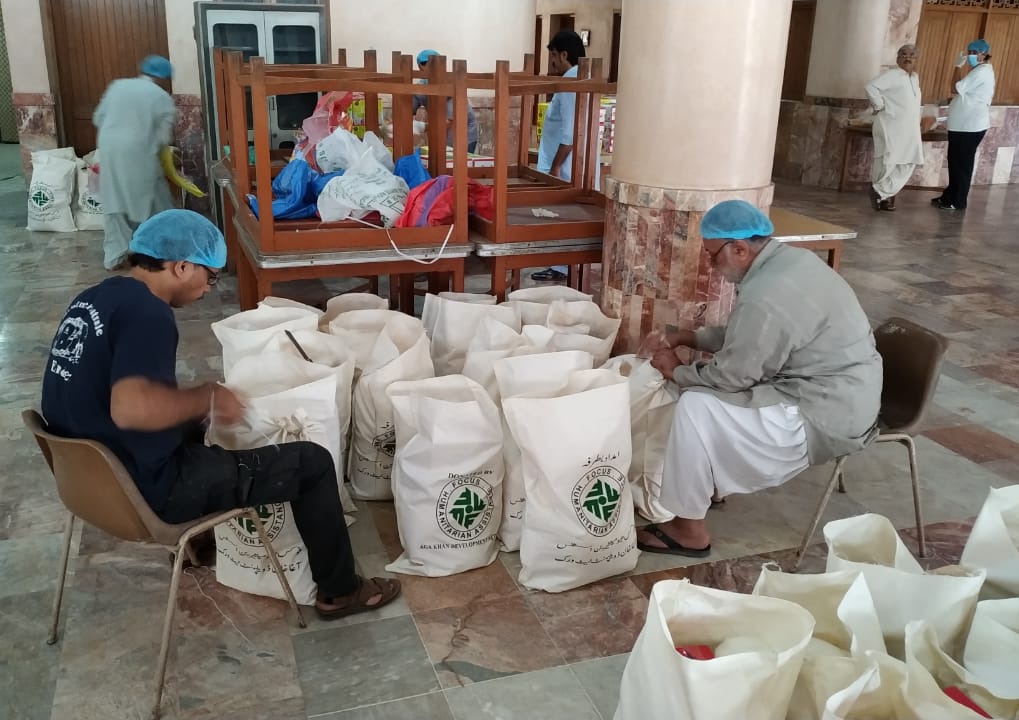 Two men work to sort large bags of food.