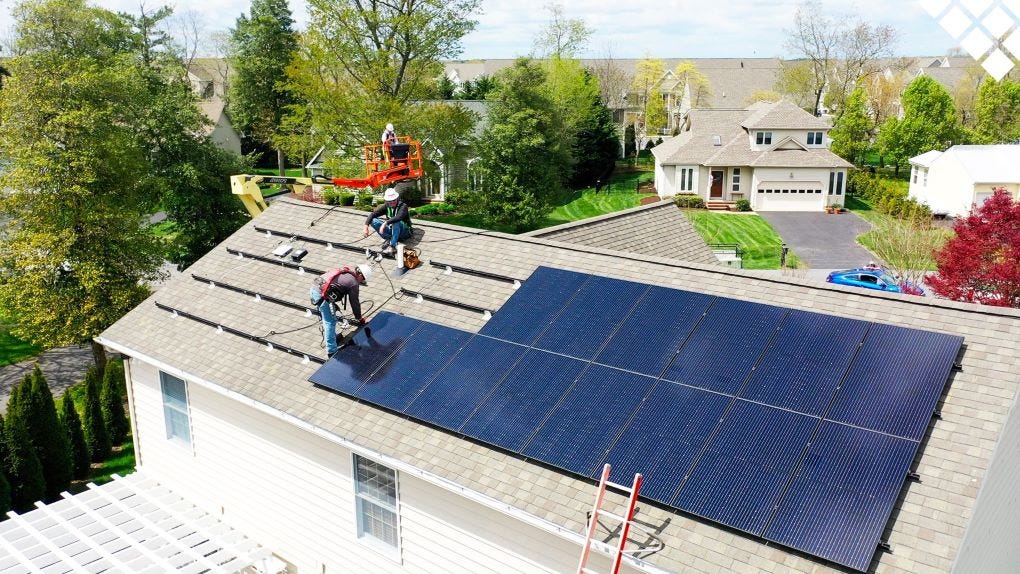 Workers installing solar panels on residential roof