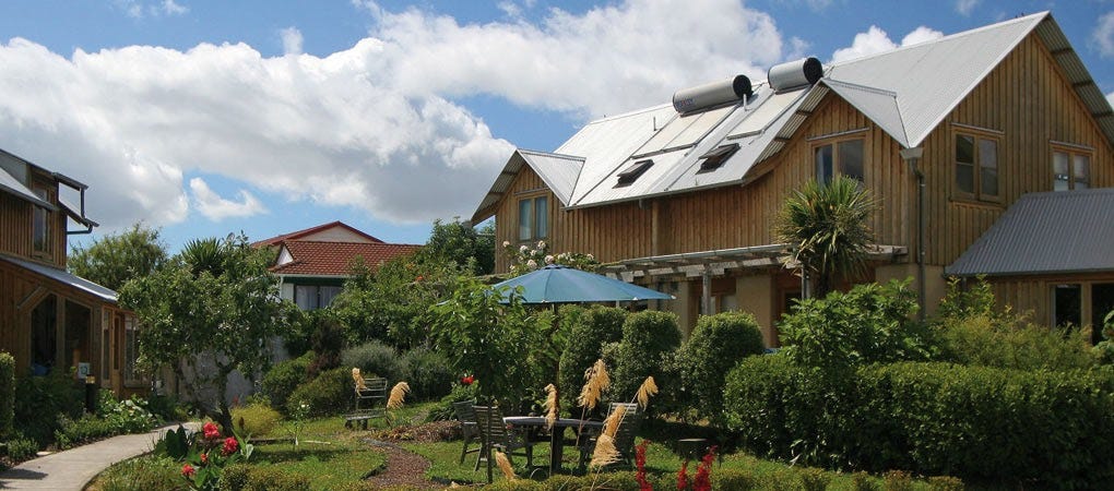 An idyllic photo of two storey houses with solar panels around a garden