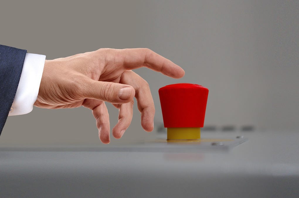 A hand is about to press an ominous-looking big red button