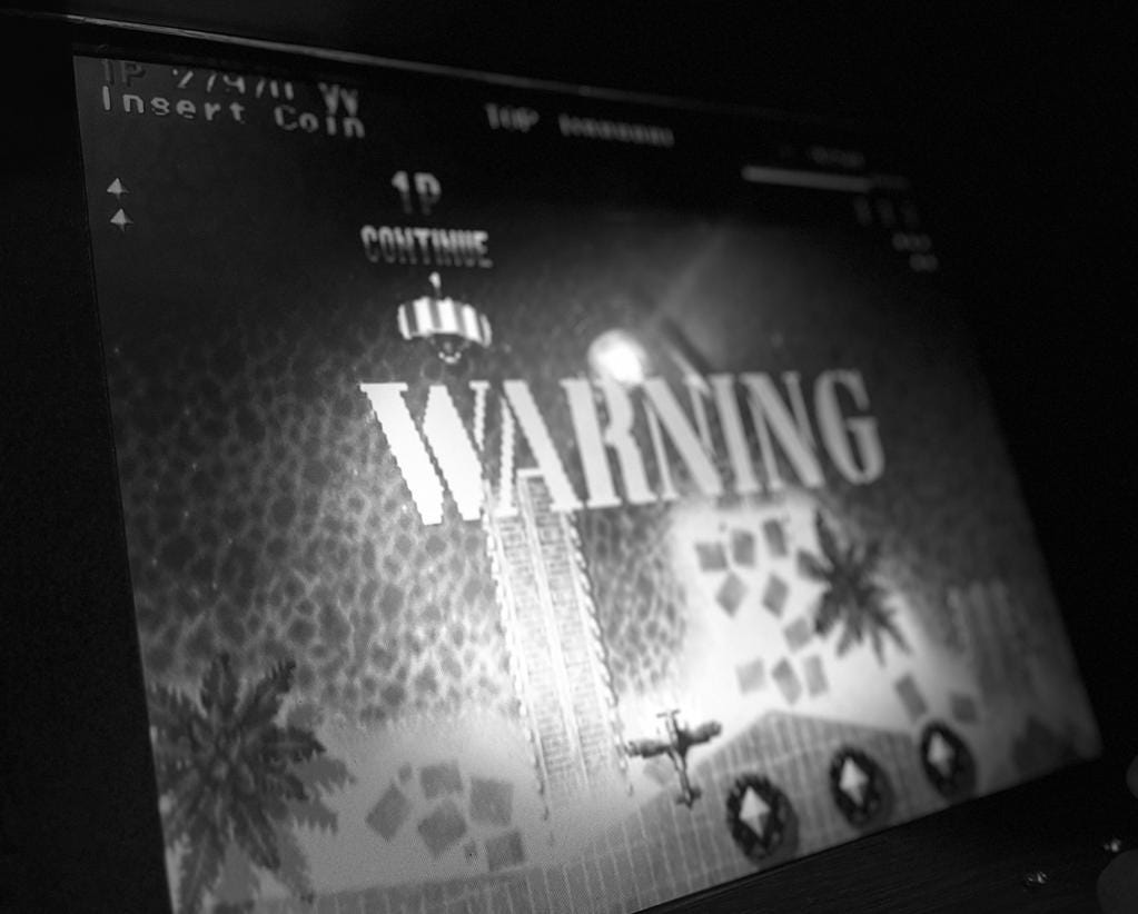 A screen showing a 1980s video war game with the word ‘Warning’ flashing