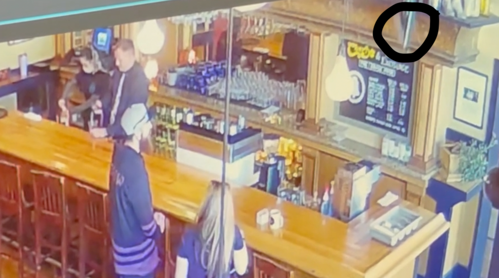 As still image from security footage showing a bottle flying off a shelf