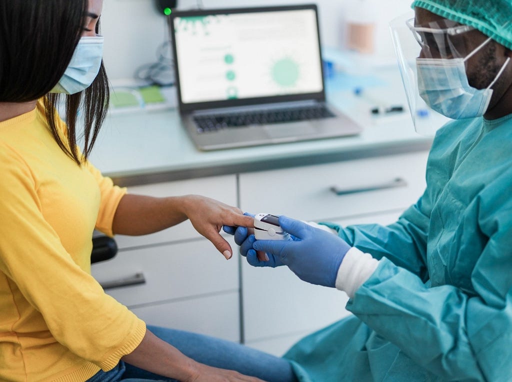 Medical staff placing a pulse oximeter on a patient’s finger. Photo by Sabrina Bracher/Getty Images