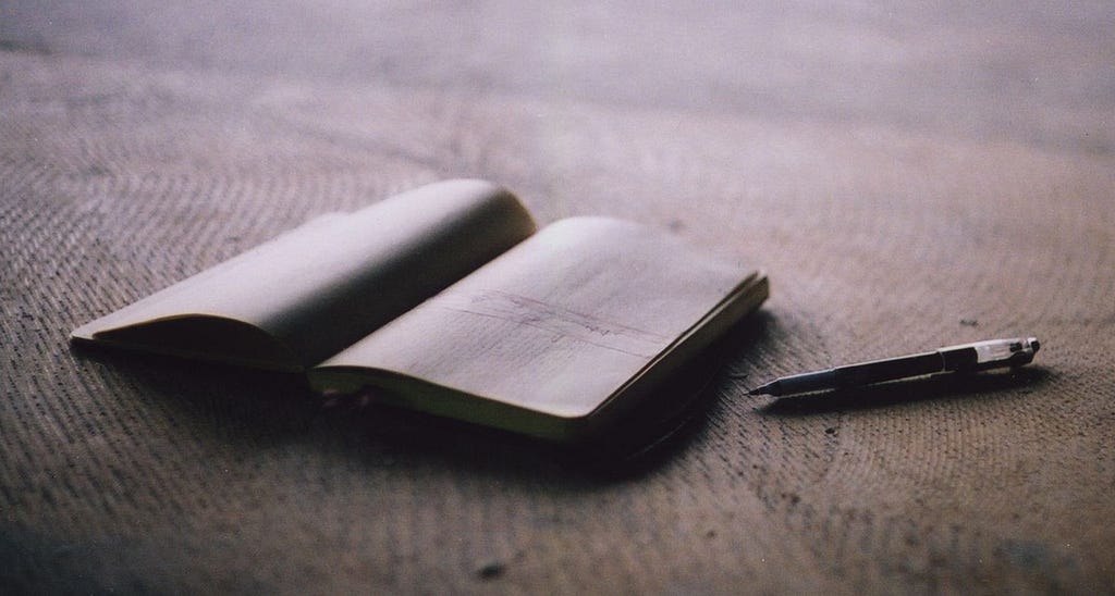 A book and pen that symbolizes the author's growth as a writer due to her always reading books.