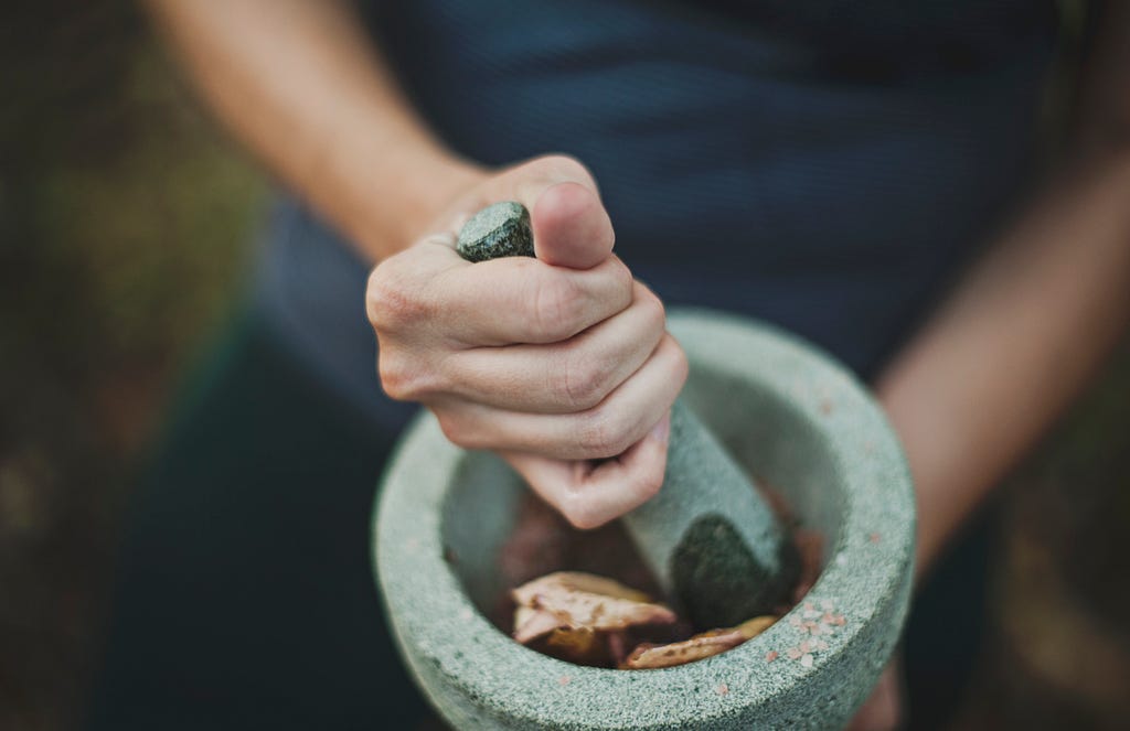 The person in the picture is shown grinding with a mortar and pestle.