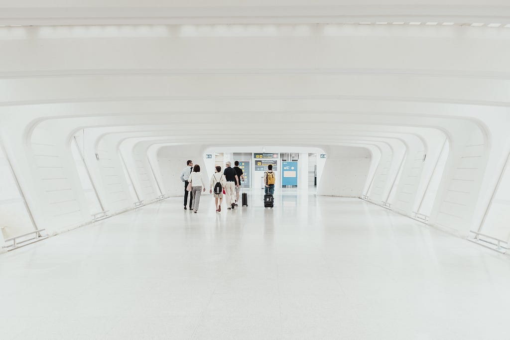 People walking in an all-white tunnel.