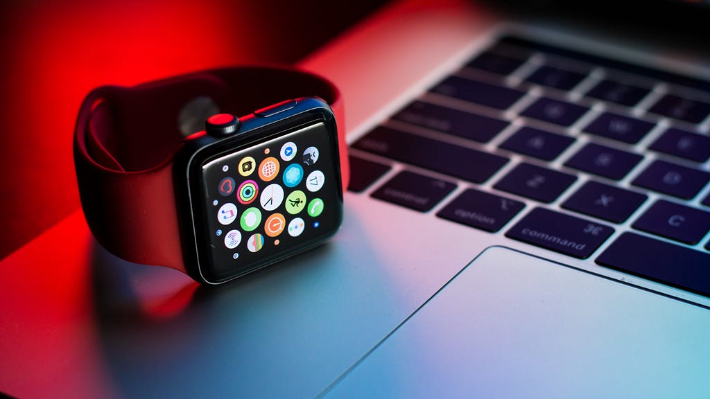 an apple watch sitting on a macbook keyboard