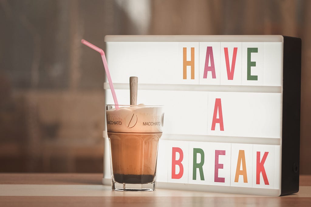 Sign that says “Have a Break” with a milkshake in front.