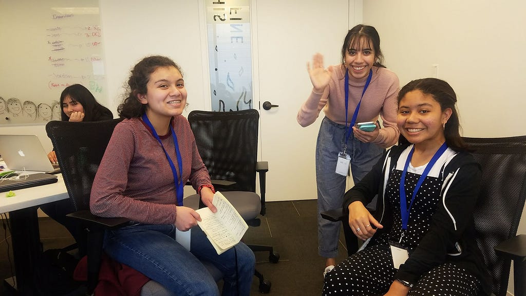 Interns waving and smiling at camera while working on project