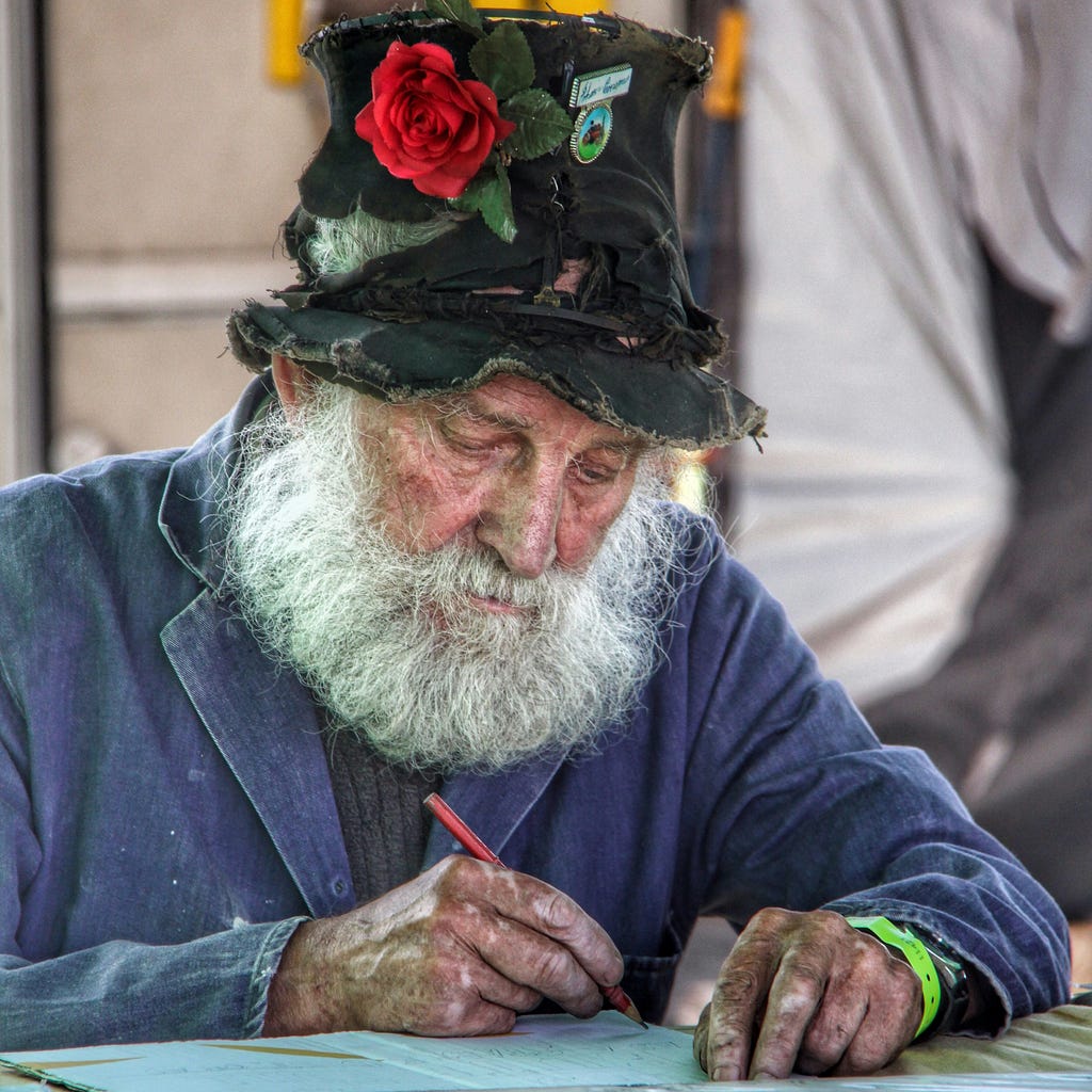 Old man with hat, sitting writing