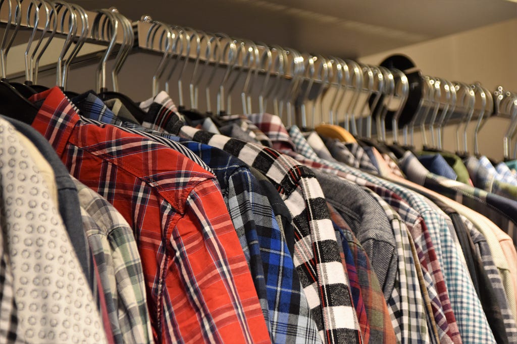 Many shirts hanging in a closet