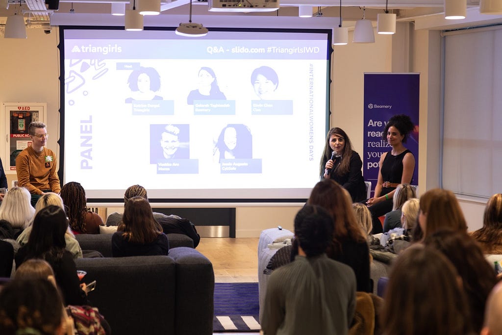 A photo of Gelareh speaking at the Triangirls IWD panel