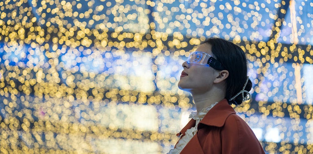 A woman wearing futuristic glasses staring upwards, while behind her there is a wall of lifts