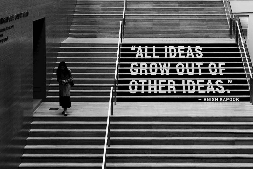 An image of a person descending a staircase, with this phrase overlaid on the stairs: All ideas grow out of other ideas. The idea is attributed to Anish Kapoor