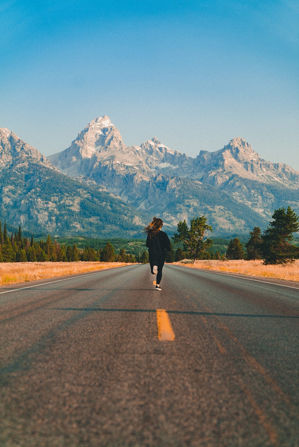 Girl running down road toward mountains