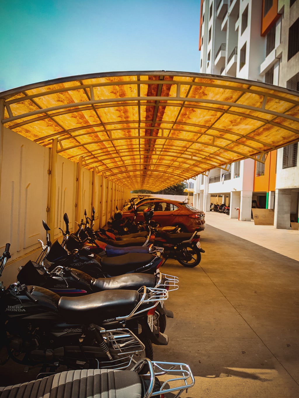 a sunny parking lot with bikes and cars in front of an office building