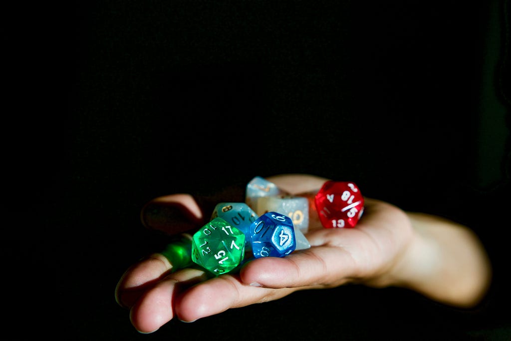 A hand holding out a set of multi-colord D&D dice