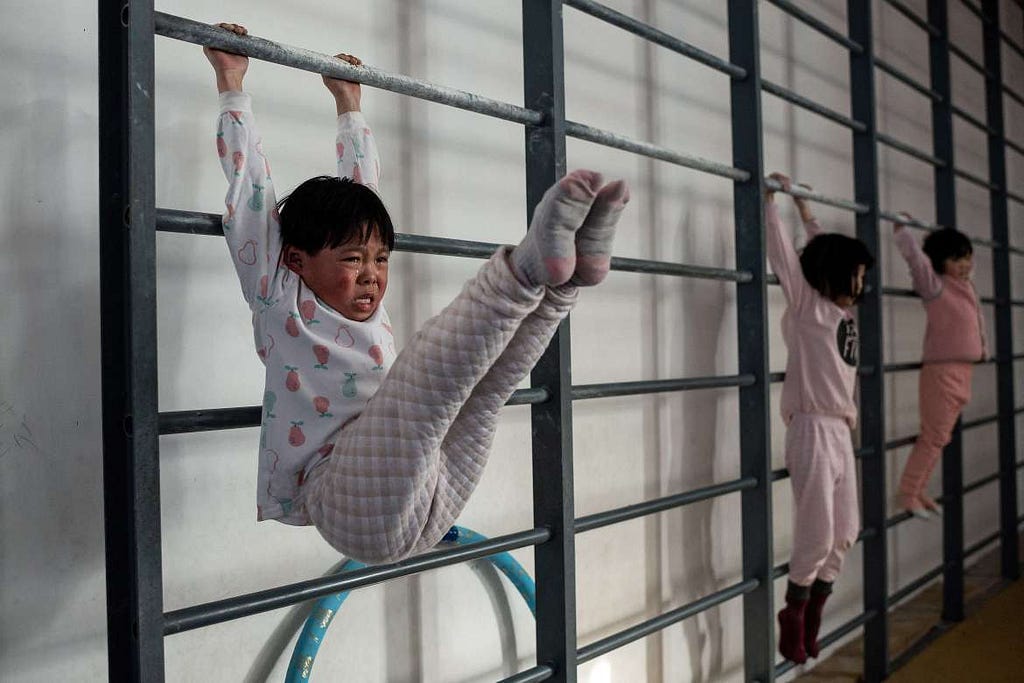 Young gymnasts train at the Li Xiaoshuang Gymnastics School. They are among the latest recruits to China’s notoriously demanding state sports system. [Nicolas Asfouri/AFP]